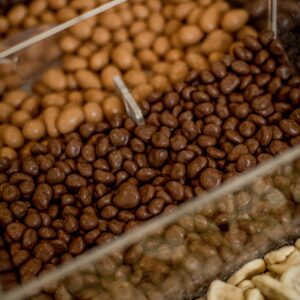 Delicious assortment of chocolate coated snacks with fruits and nuts in a retail display.