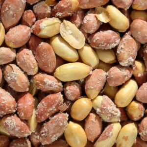 A detailed close-up photograph of salted peanuts with shells, showcasing texture.