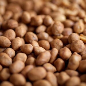 A detailed close-up of numerous salted peanuts creating a textured background.