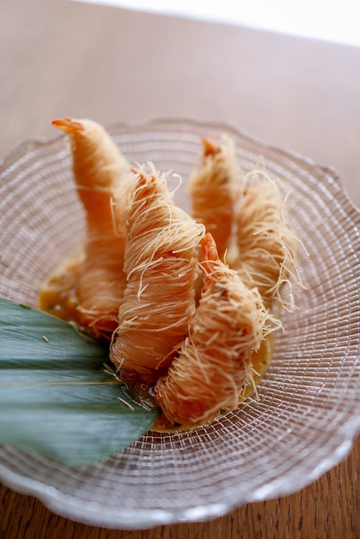 Close-up of perfectly cooked kataifi-wrapped shrimp served on a decorative plate.